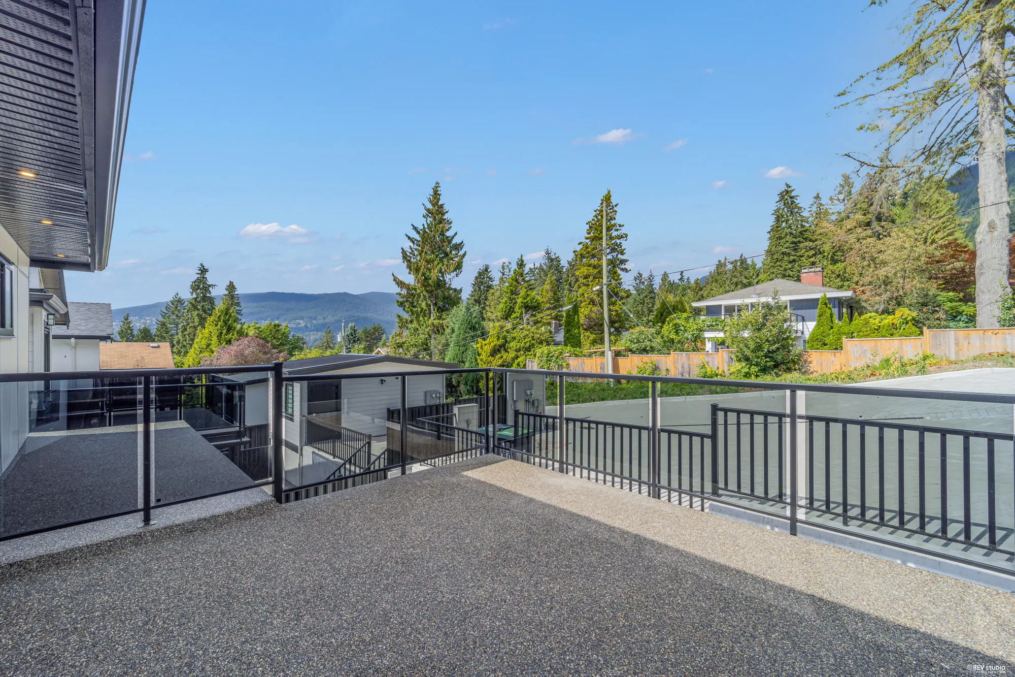 From the balcony: the deck below, the neighbours' roofs, the trees and the slopes beyond