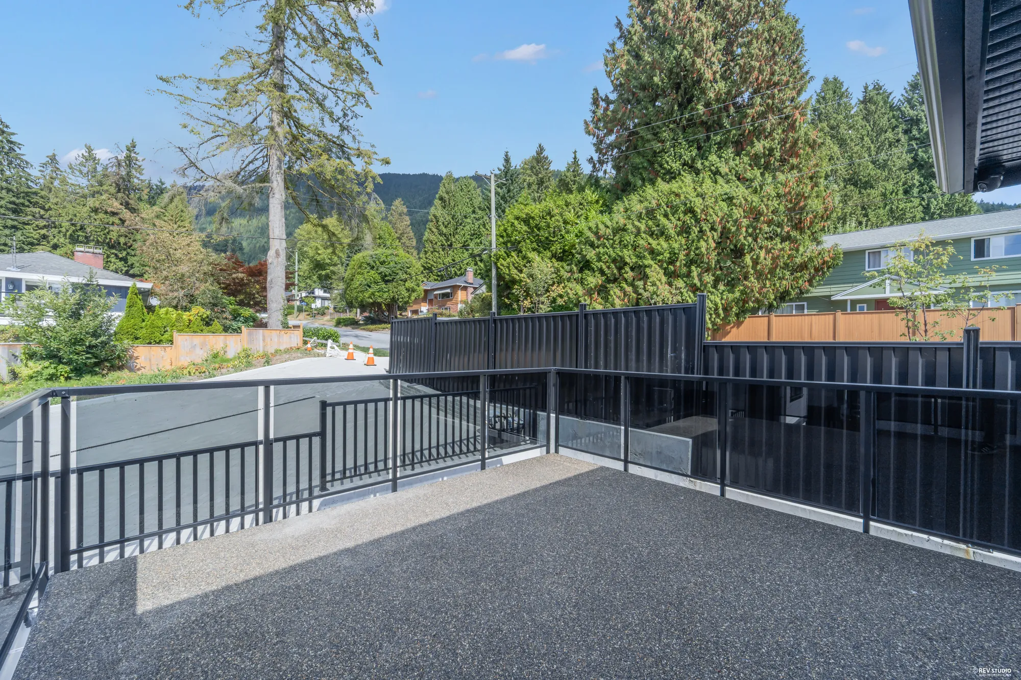 Along the balcony's black privacy screen, the lane and the neighbours beyond