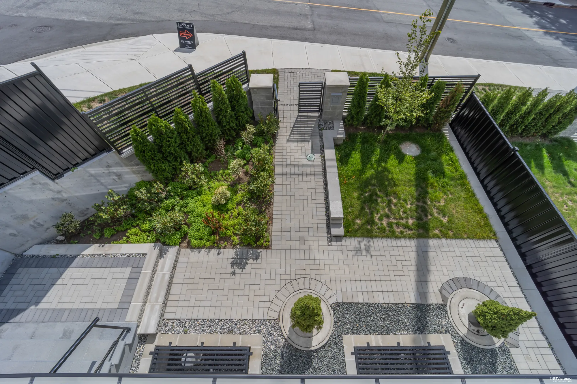Looking down from the balcony onto the front garden's turf, pavers and planters