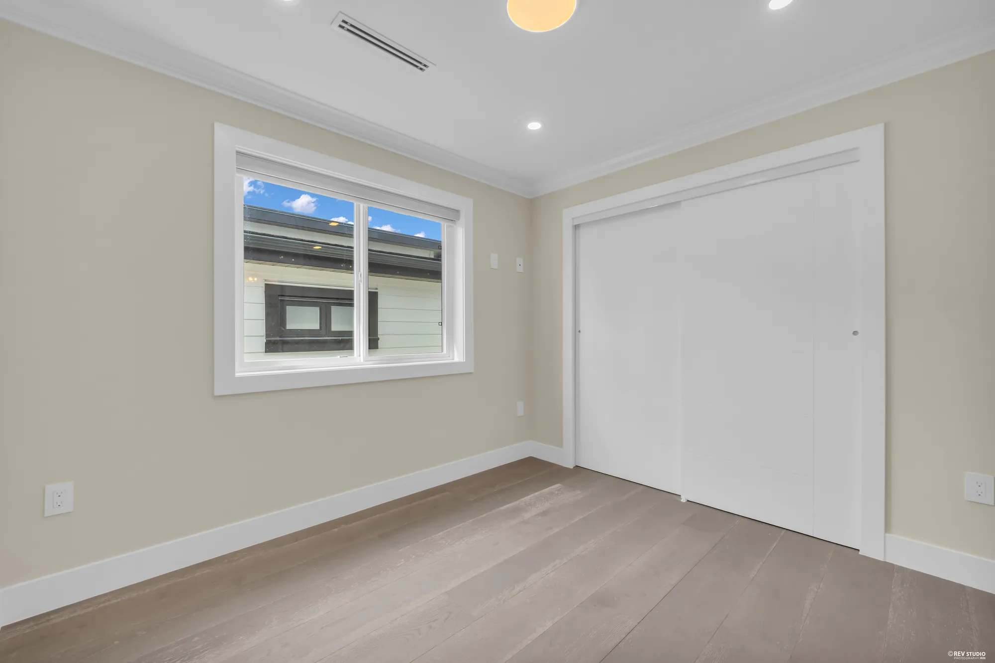 A bedroom with sliding closet doors and a window