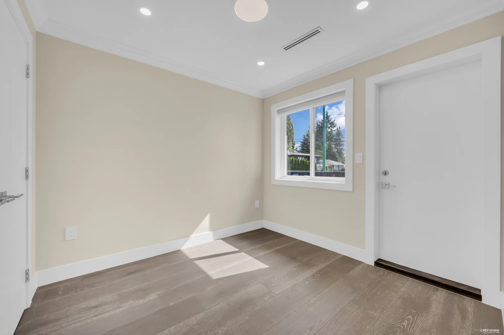 A bedroom with a window and a door, wood floor