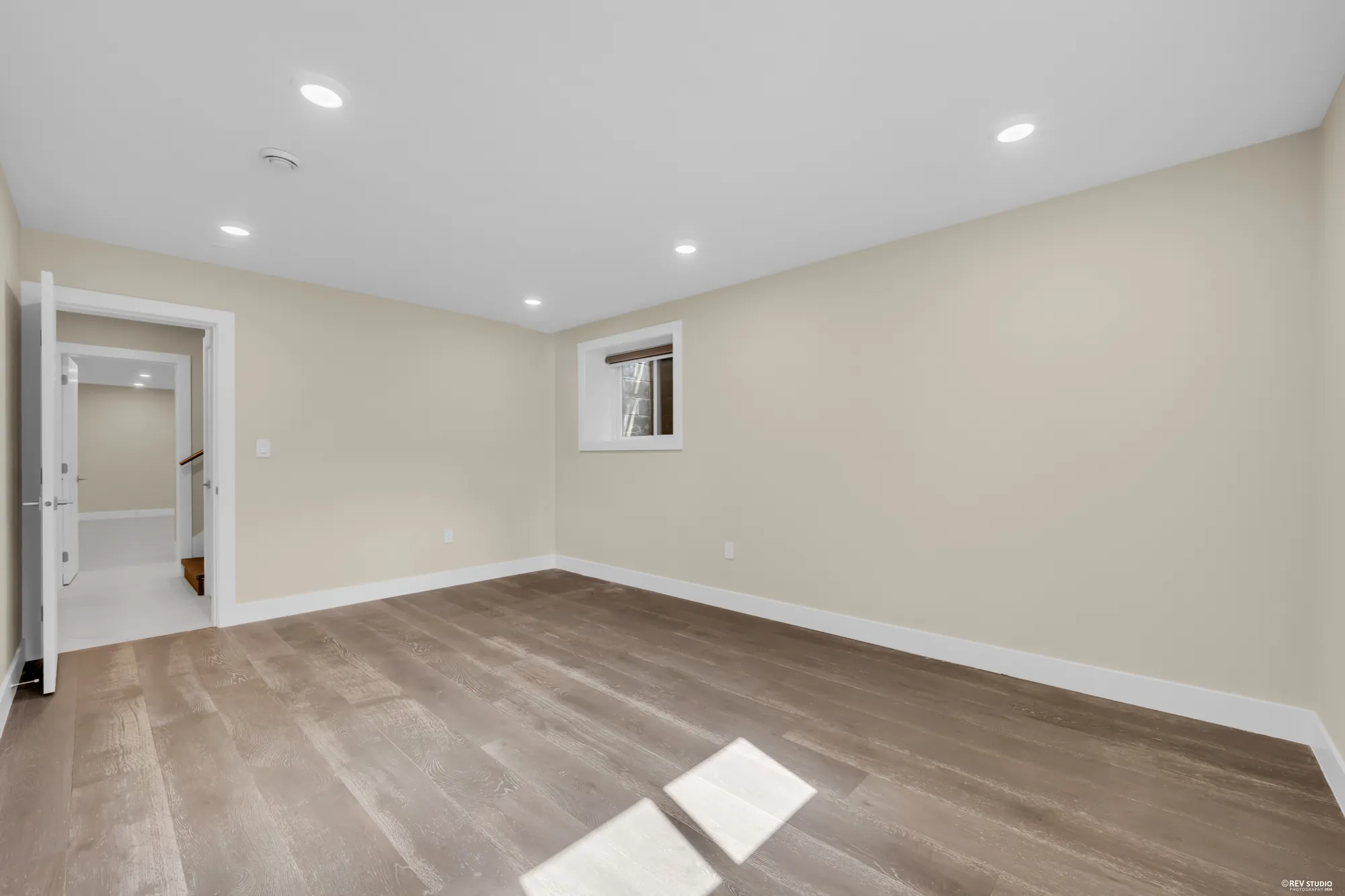 A lower bedroom toward its door, a small window on the far wall