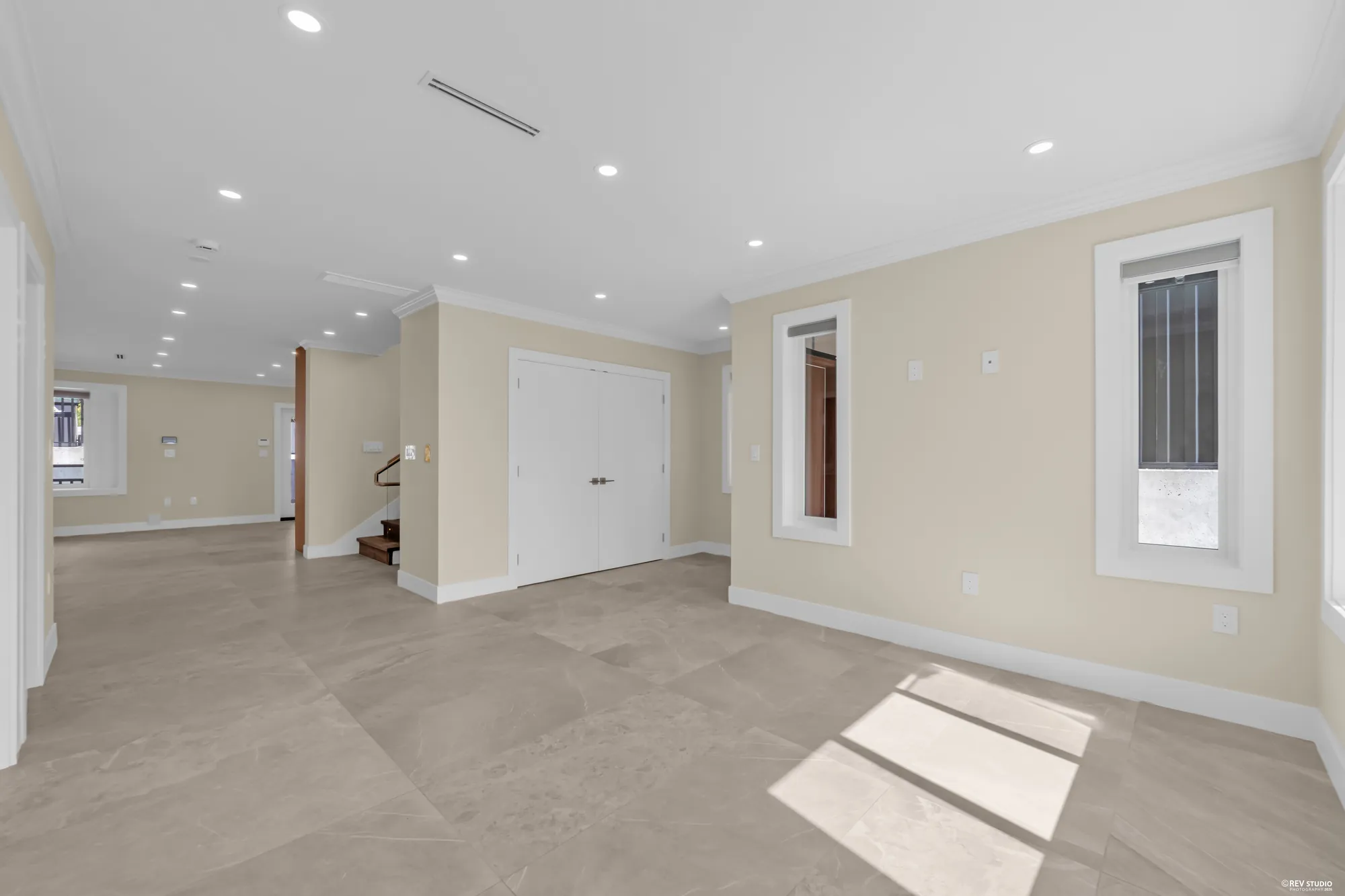 The living room at the front: pale stone-look tile, double doors to the foyer, windows onto the street