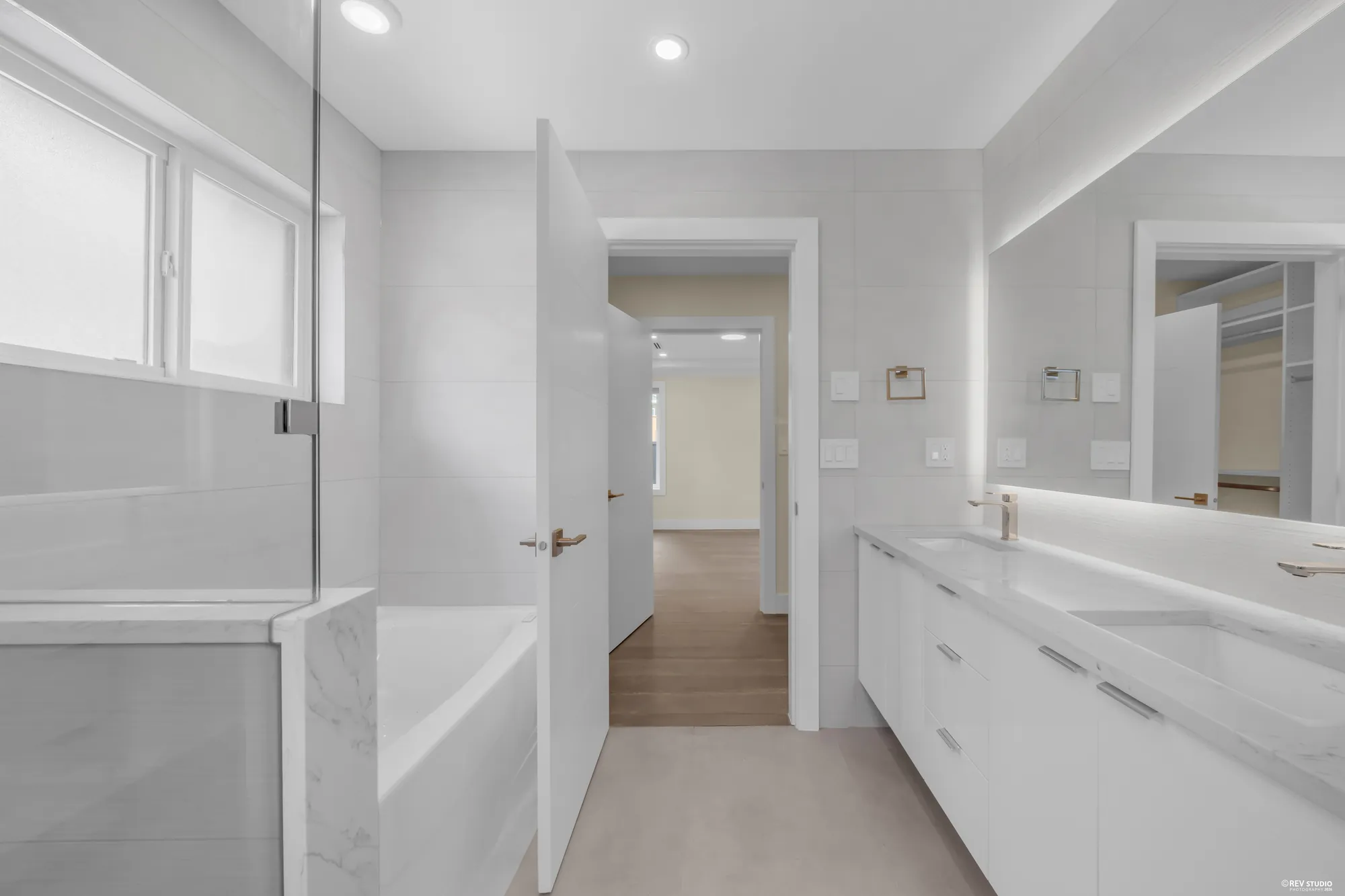 The primary bathroom's tub beside the vanity, the hall through the door