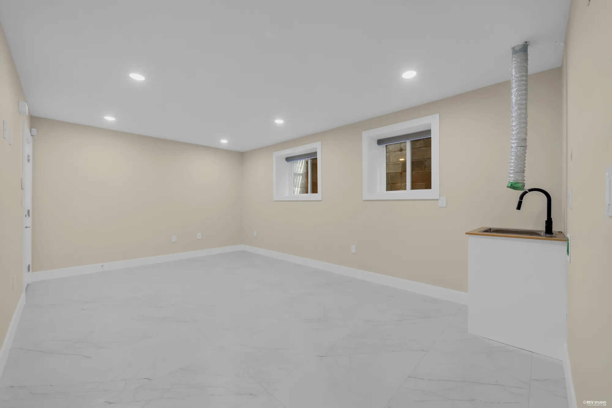 The recreation room: a long tiled room with a bar sink and cabinet at the far end