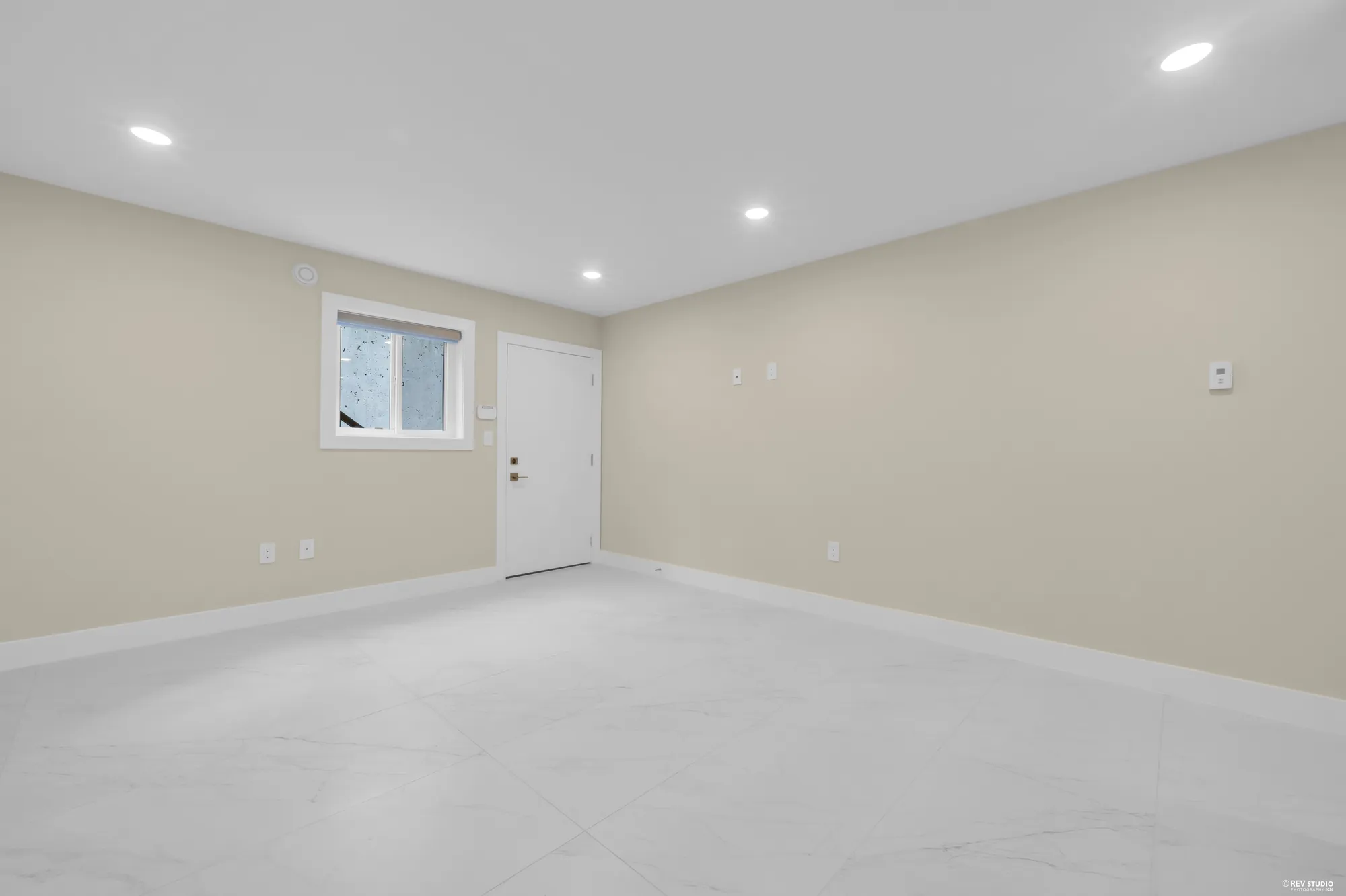 The living area on the lower floor: tiled, a window on the side wall, the door to the patio at the end