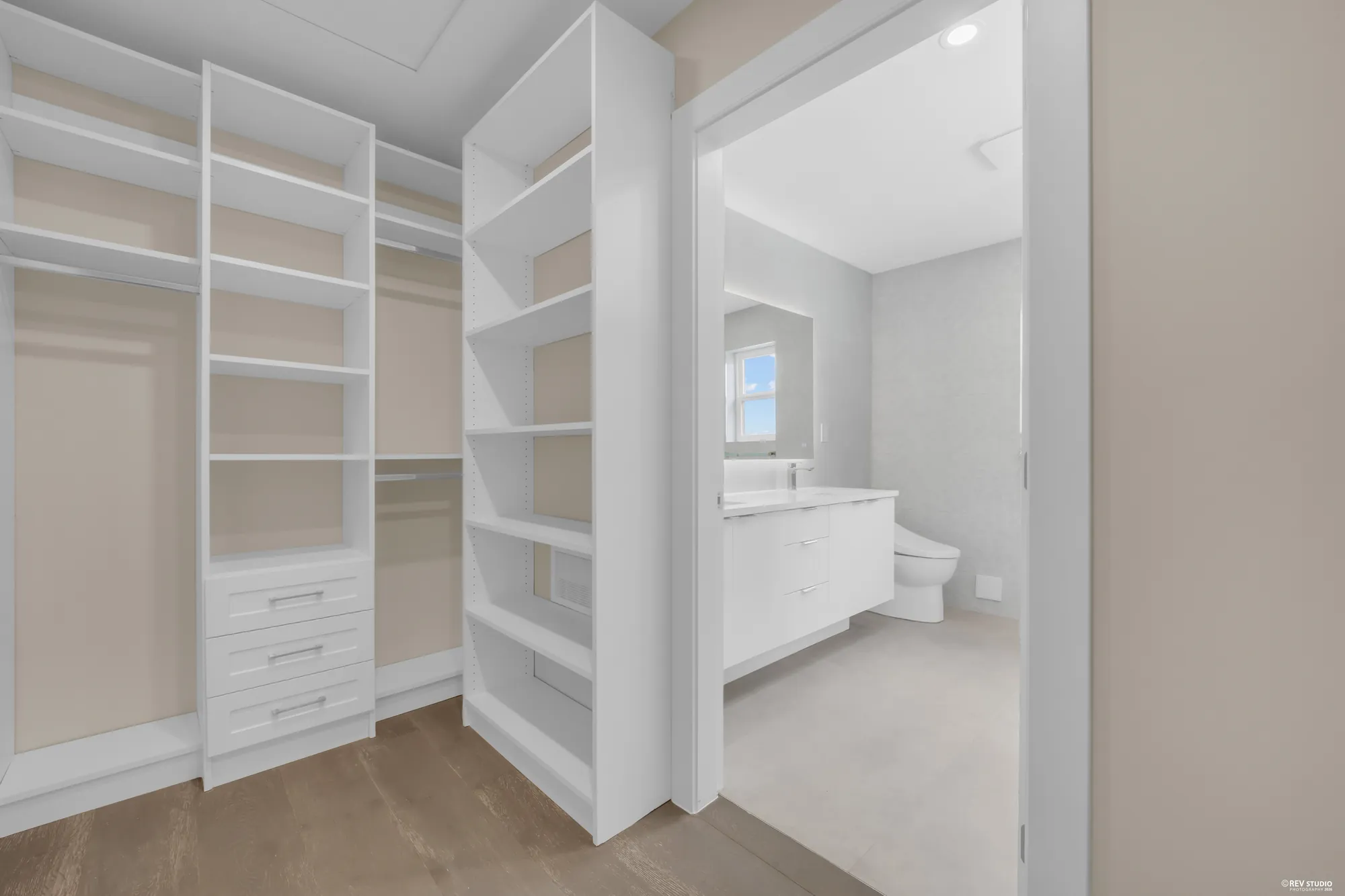 The walk-in closet fitted in white, the primary bathroom beyond its door